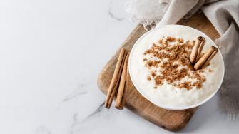 Arroz con leche. Rice pudding with cinnamon in clay bowl on white marble. Top view