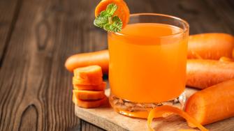 Carrot juice in glass on wooden table.
